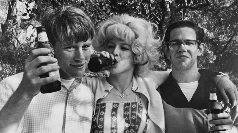 Ron Howard, Candy Clark, and Charles Martin Smith drinking beers on the set of American Graffiti.