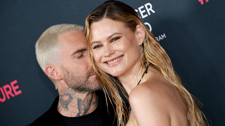 Blond-haired Adam Levine embracing Behati Prinsloo