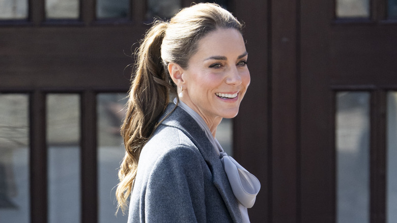 A smiling Princess Catherine sporting a sleek ponytail and a grey blazer