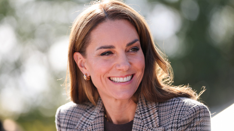 Princess Catherine smiling in a check blazer and gold earrings