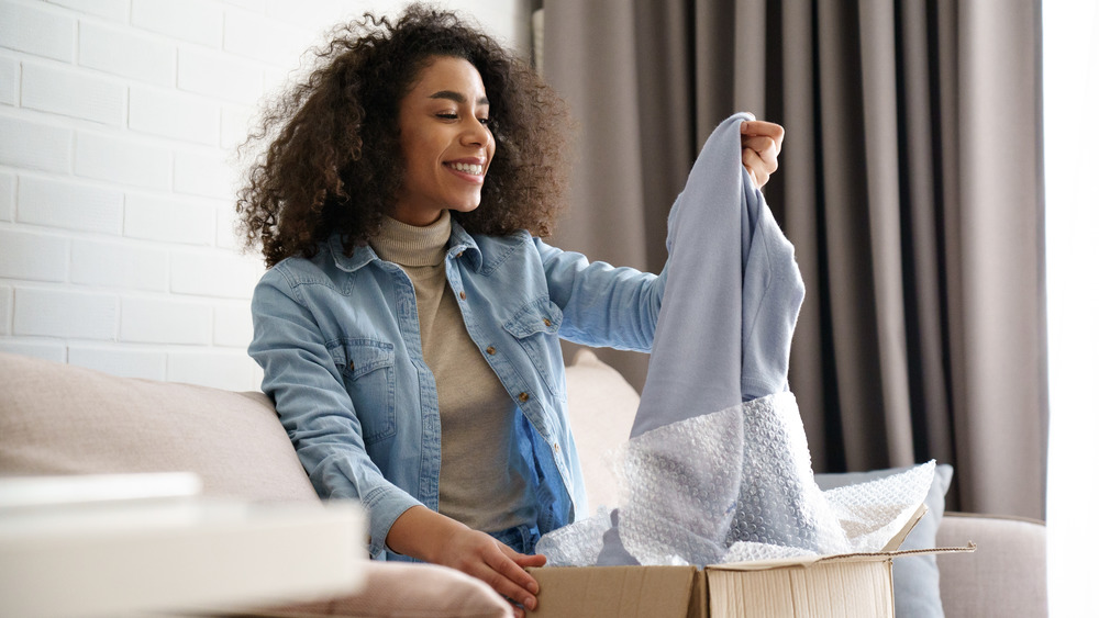 Woman unboxing clothes from shopping haul