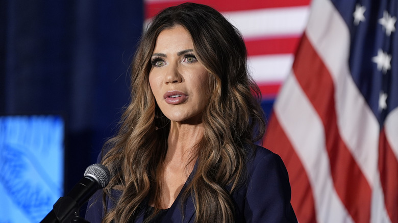 Kristi Noem giving a speech in front of an American flag