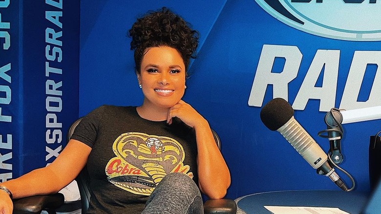 Joy Taylor smiles sitting in front of a microphone at a radio station.
