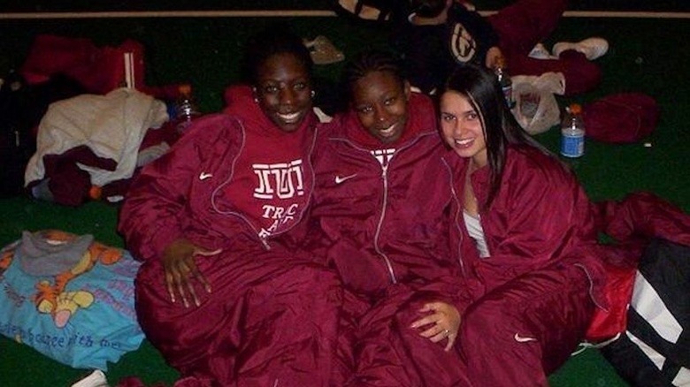 Joy Taylor sitting next to two other athletes in red track suits