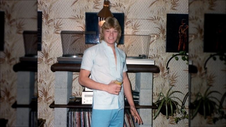 Young Mike Holmes smiling in front of a record console