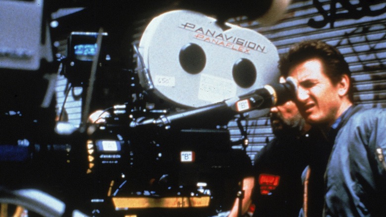 Sean Penn looking into the viewfinder of a camera in 1990