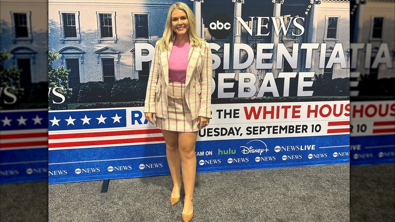 Karoline Leavitt wearing a beige and pink plaid suit at a debate