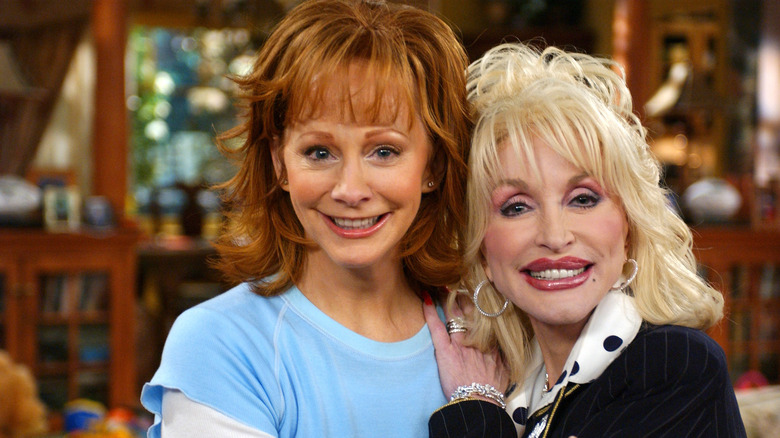 Reba McEntire and Dolly Parton smiling while posing together