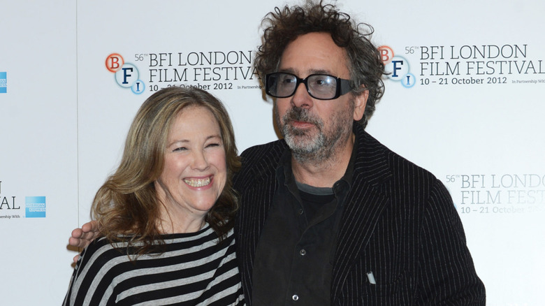 Catherine O'Hara in a black and white striped shirt, Tim Burton in a black suit