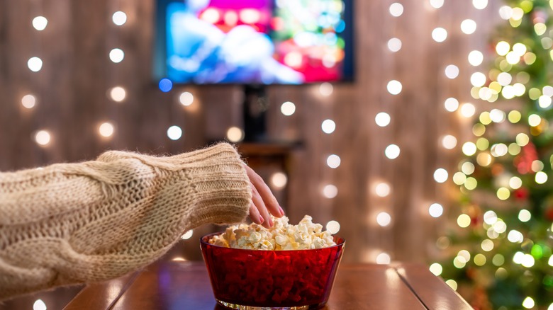 Woman watching holiday movie and eating popcorn