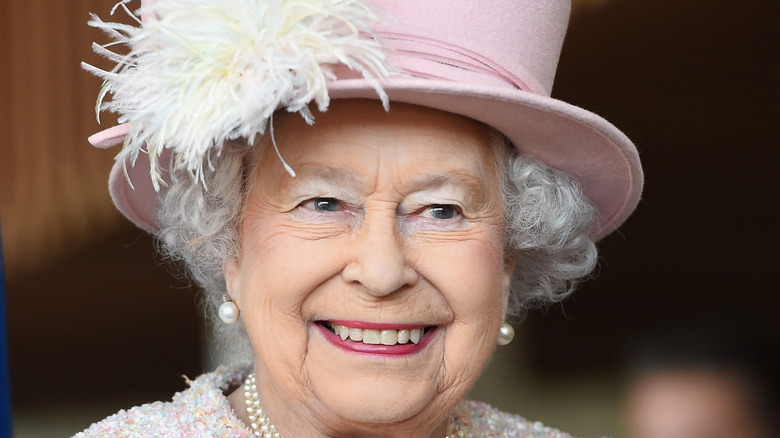 Queen Elizabeth II smiling in pink hat