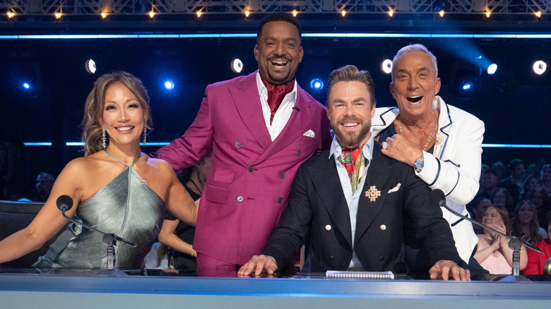 Carrie Ann Inaba, Alfonso Ribeiro, Derek Hough, and Bruno Tonioli, all smiling behind the "Dancing with the Stars" judging panel