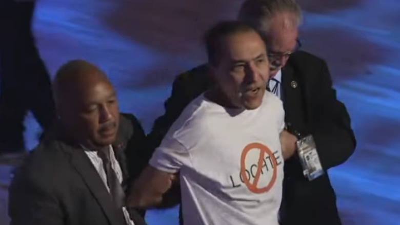 A protestor wearing an anti-Ryan Lochte t-shirt being carried away by security