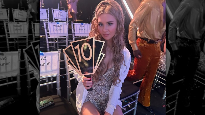 Anna Delvey holding up a 10 scorecard behind the scenes on "Dancing with the Stars"