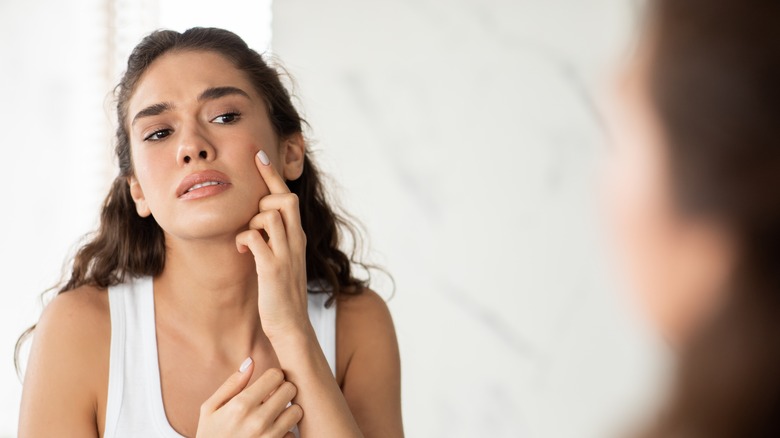 Woman looking in the mirror at pimple