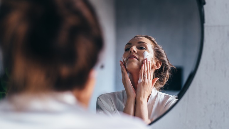 woman scrubbing face in mirror