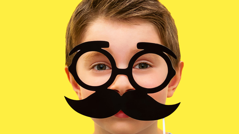 Kid smiling with a mustache disguise