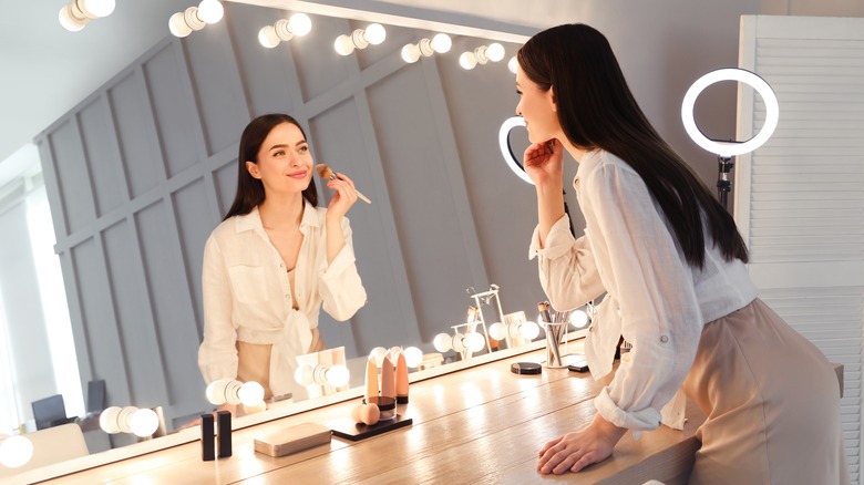 Woman applying makeup in mirror