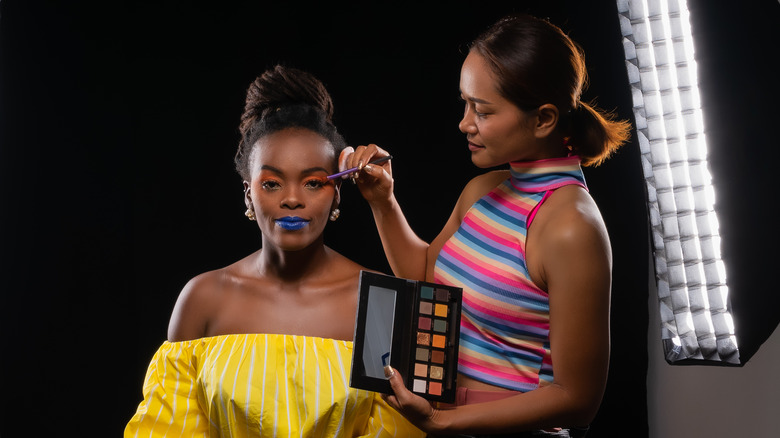 Makeup artist applying makeup to a model. 