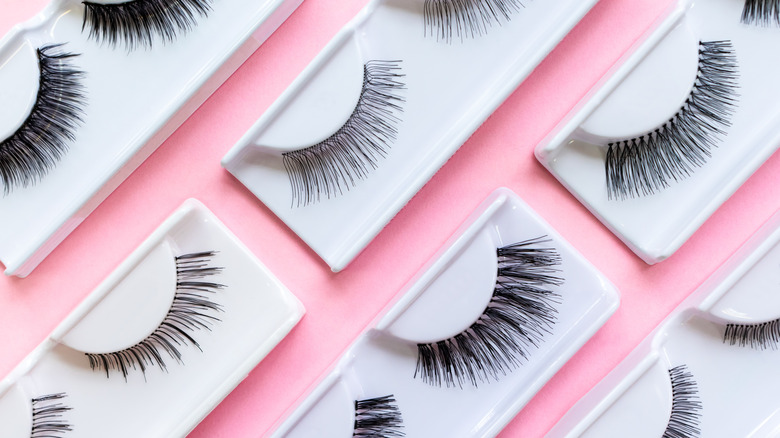 Several sets of false eyelashes on a pink background.