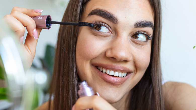 Woman smiling and applying mascara