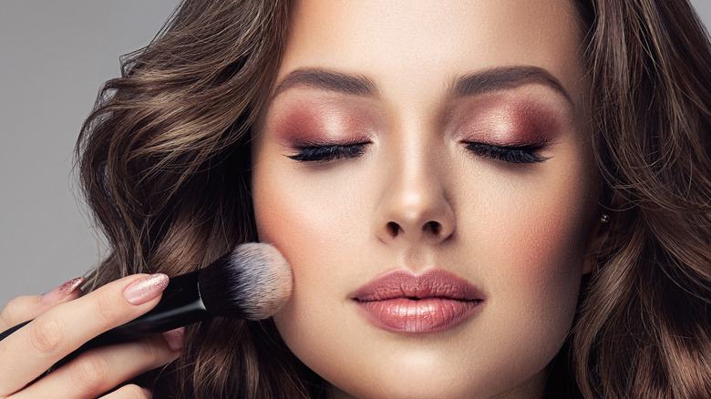 A woman putting setting powder on her face