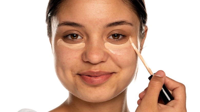 woman applies concealer directly beneath her eyes