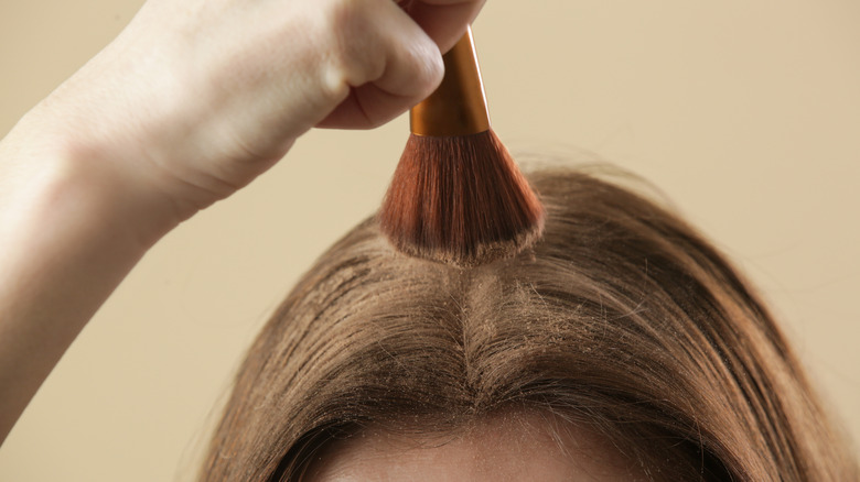 Applying dry shampoo to hair roots