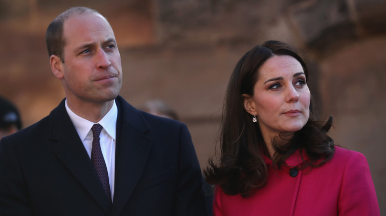 Prince William and Kate Middleton looking concerned at something in the distance