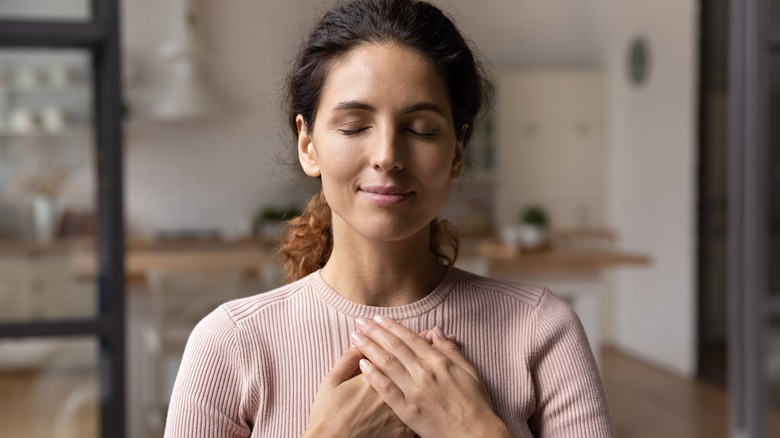 A woman holding her hands over her heart