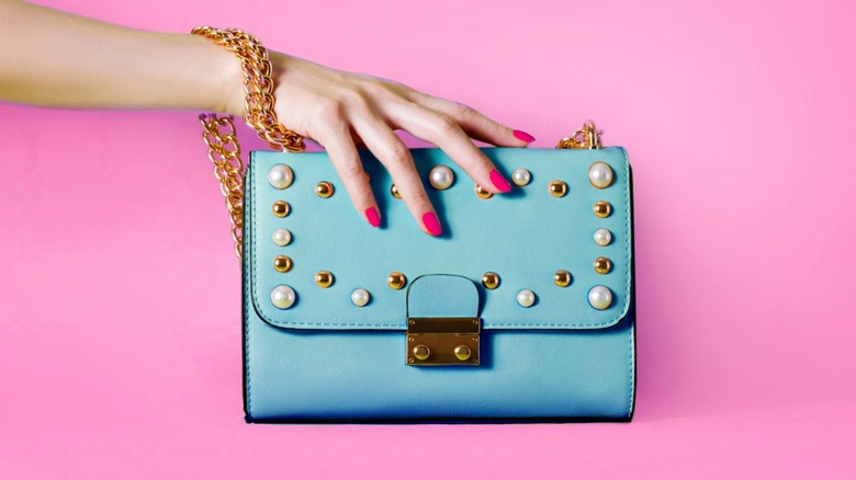 woman holding turquoise purse pink nails