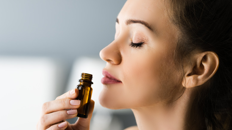 Woman sniffs essential oil bottle