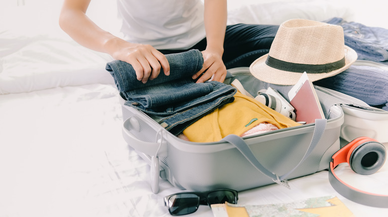 Woman folding jeans in a suitcase