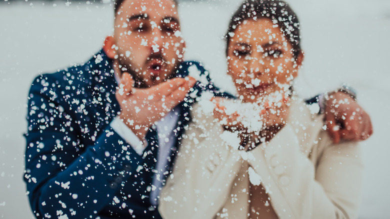 Couple blowing snow at winter wedding
