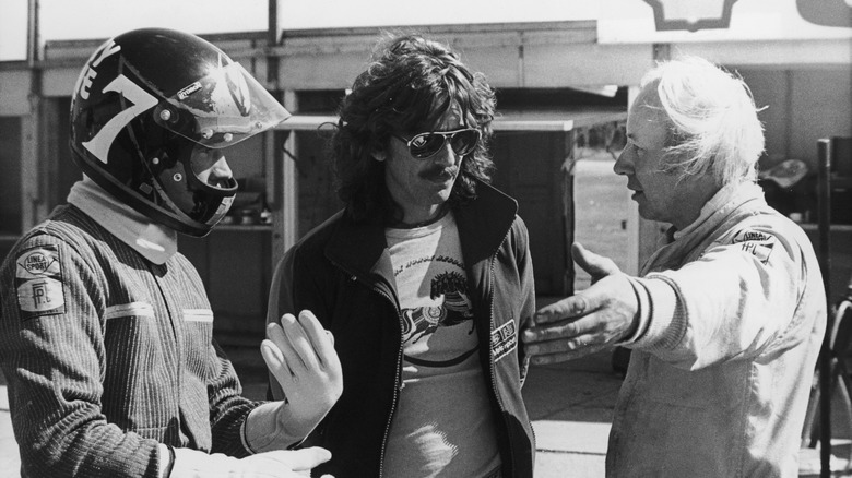 British motorbike champion Barry Sheene (1950 - 2003, left) at Brands Hatch, where he is driving a Formula One racecar for the first time, 25th April 1978. Also present at the track are keen racing fan George Harrison (1943 - 2001, centre) of the Beatles, and advisor John Surtees (right), who successfully made the transition from motorcycle racing to Formula One.