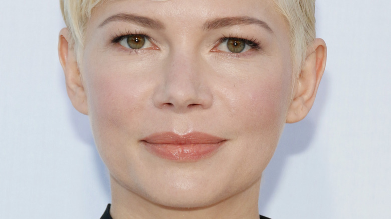 Michelle Williams with a short platinum blonde pixie cut posing for the camera