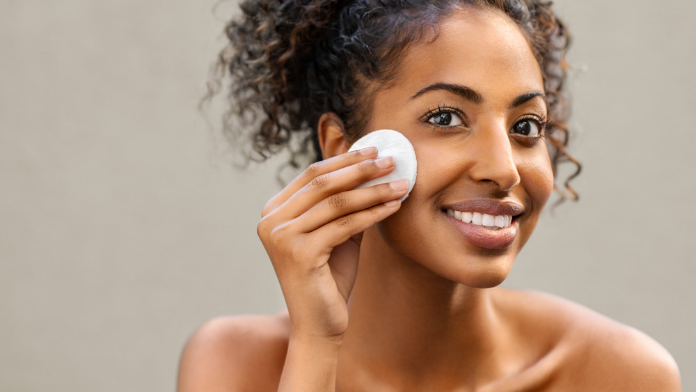 Woman applying cotton pad to face