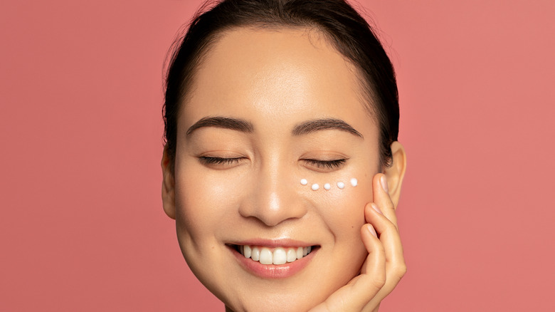 Woman smiling with eye cream underneath her eye