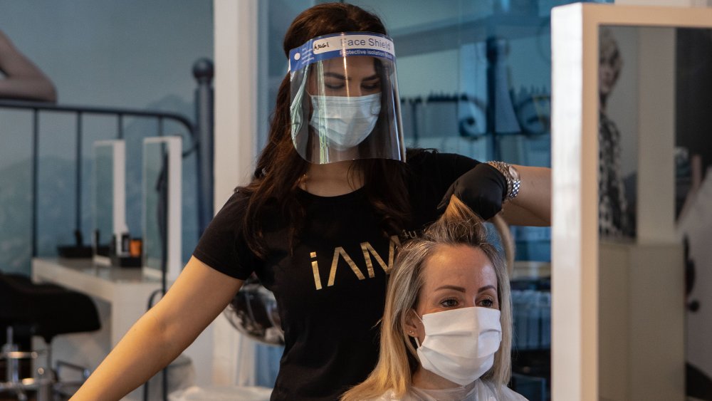 Woman getting hair cut while wearing a face mask