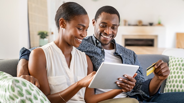 couple smiling and looking at a tablet