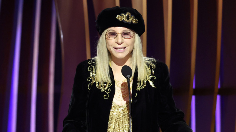 Barbra Streisand wearing black behind a microphone
