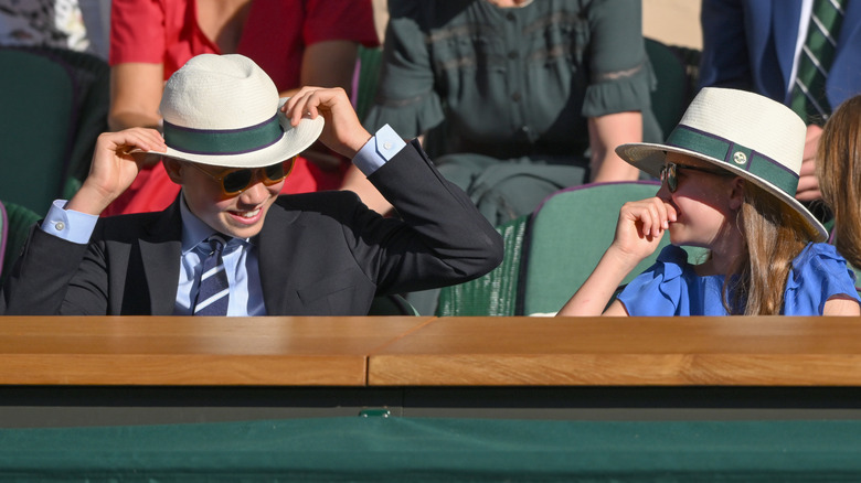 Prince George pulling down his hat at Wimbledon as Princess Charlotte laughs