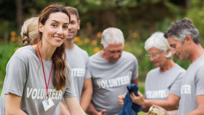 Young woman wearing lanyard and shirt that reads volunteer amid a group of other volunteers
