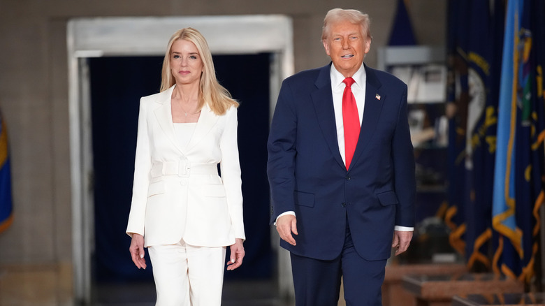 President Donald Trump and Pam Bondi walk through the Justice Department in March 2024 with him in a blue suit and her in a white suit