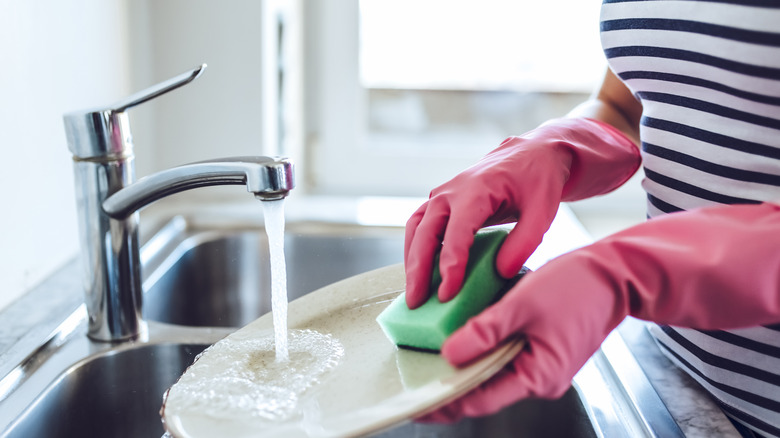 person washing dishes with gloves