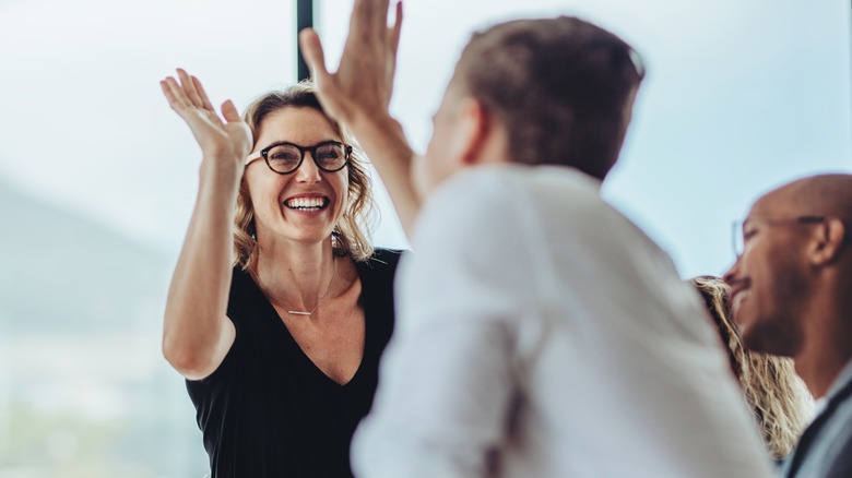 A woman high fiving colleagues in a room