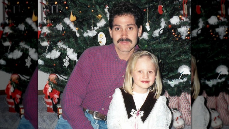 Tomi Lahren as a child posing with her dad in front of a Christmas tree