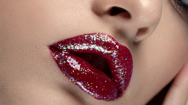 Red glitter lip gloss on lips 