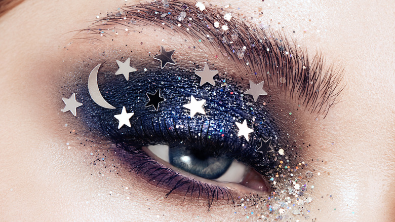 woman's eye with heavy makeup, glitter, and sequins