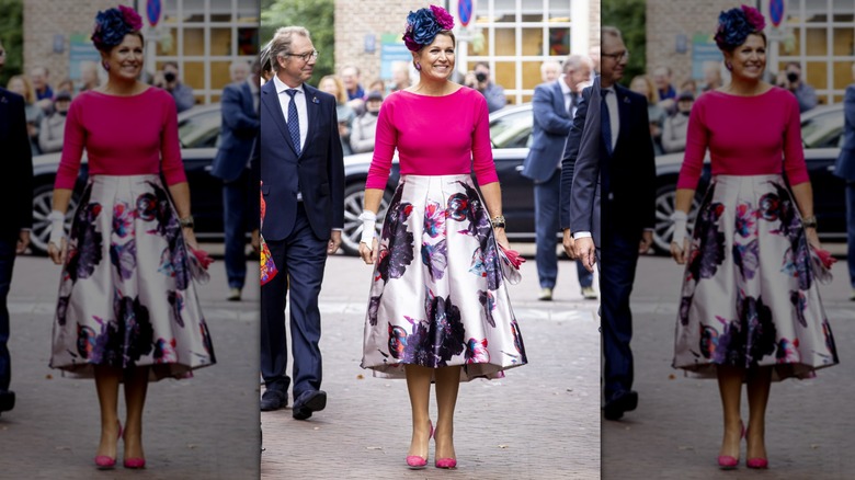 Queen Máxima walks smiling in a floral headpiece and floral skirt to a Frida Kahlo exhibit.